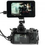 A small rectangle monitor showing a steam train fixed to the top of a camera