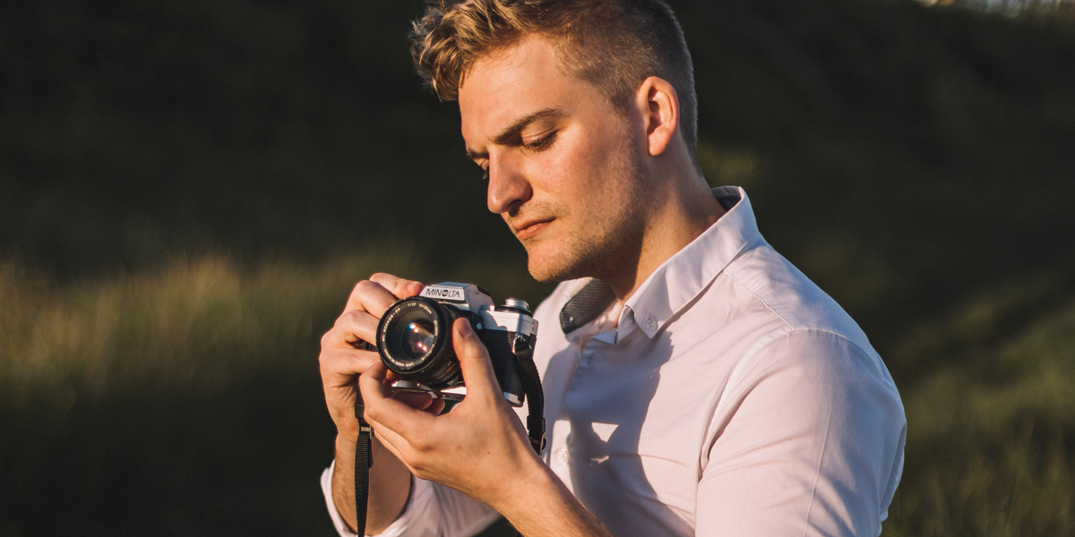 Movie director posing with camera in in orange hue light