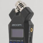A black Zoom H1Essential recording device standing vertically