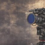 A camera on a stand in front of a brown and grey wall