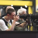 A young man looking through a large camera and lens