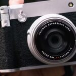 A hand holding a small fixed-lens camera