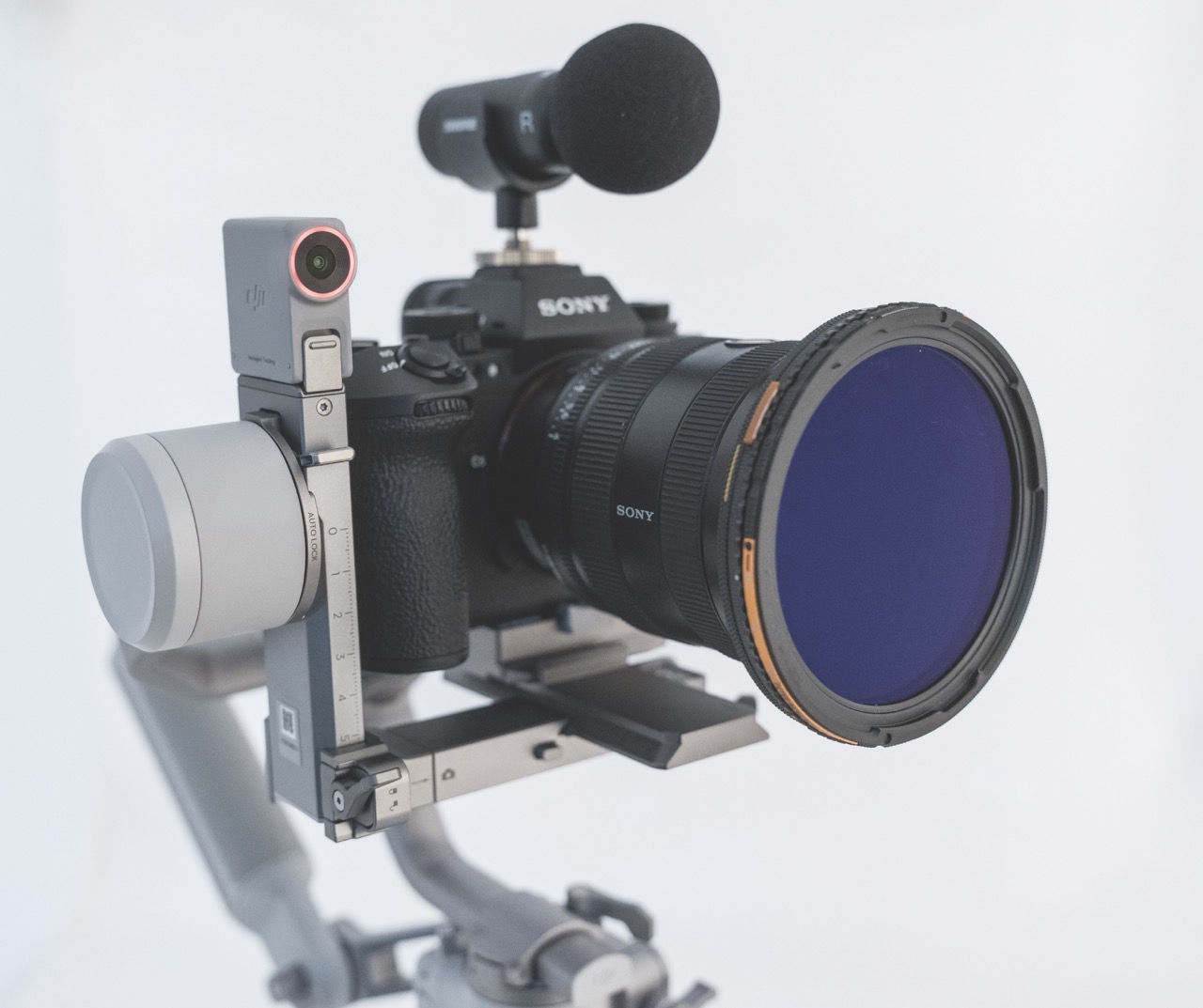 The front of a professional camera with a microphone attached to the top set up on a gimbal