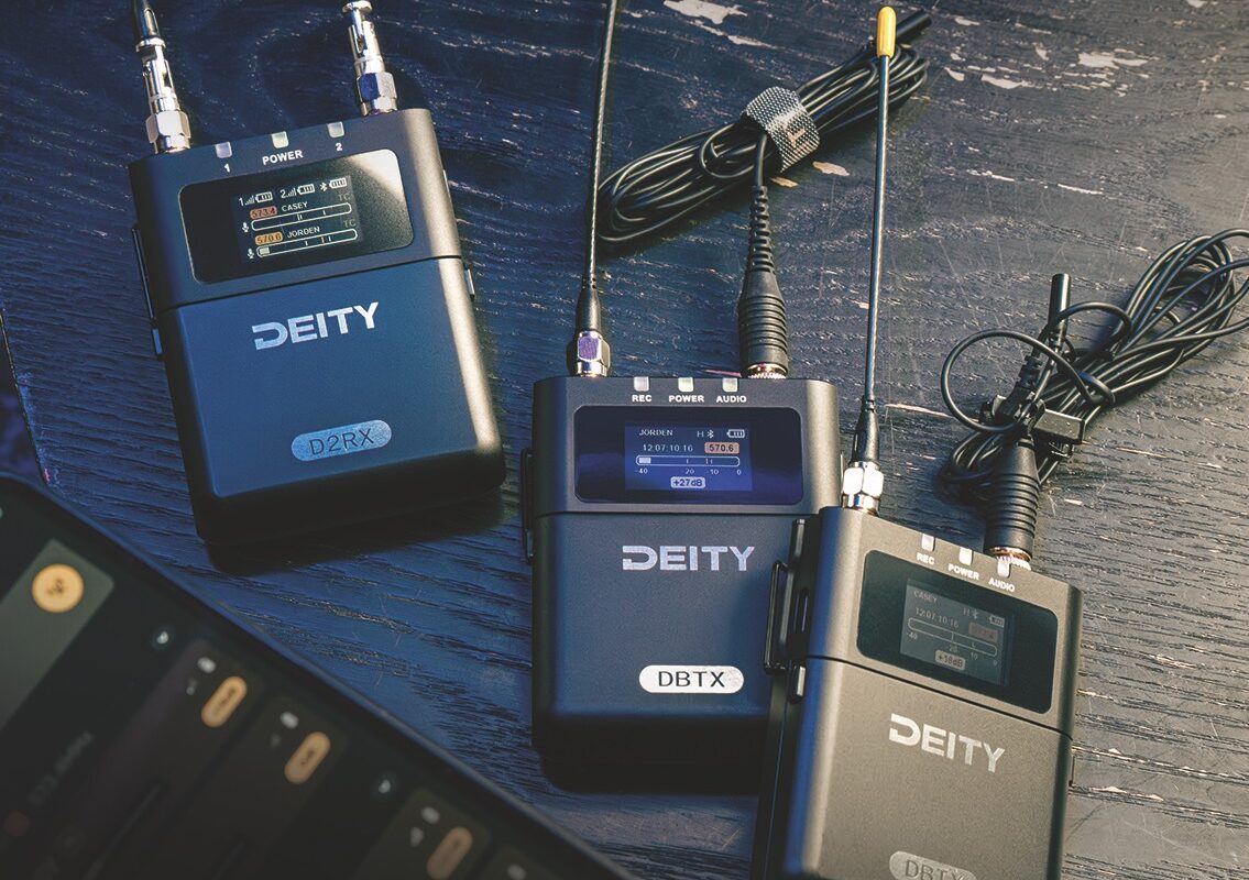 Three microphone packs with wires wrapped up. They lay on a table slightly overlapping