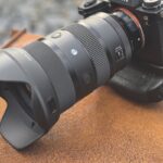 A camera with a large lens resting on an orange surface outside