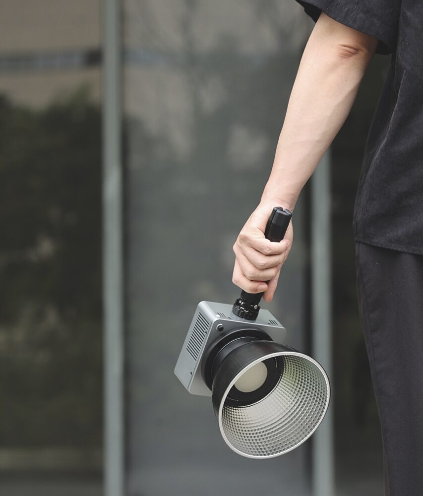 Someone holds a large light attached to a rod