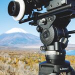 The joints of a tripod being used outside in front of a mountain landscape