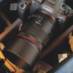 A Canon camera with a large lens placed in a blue bag