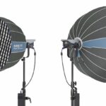 Two professional lighting umbrellas on stands. One faces back while the other faces forward