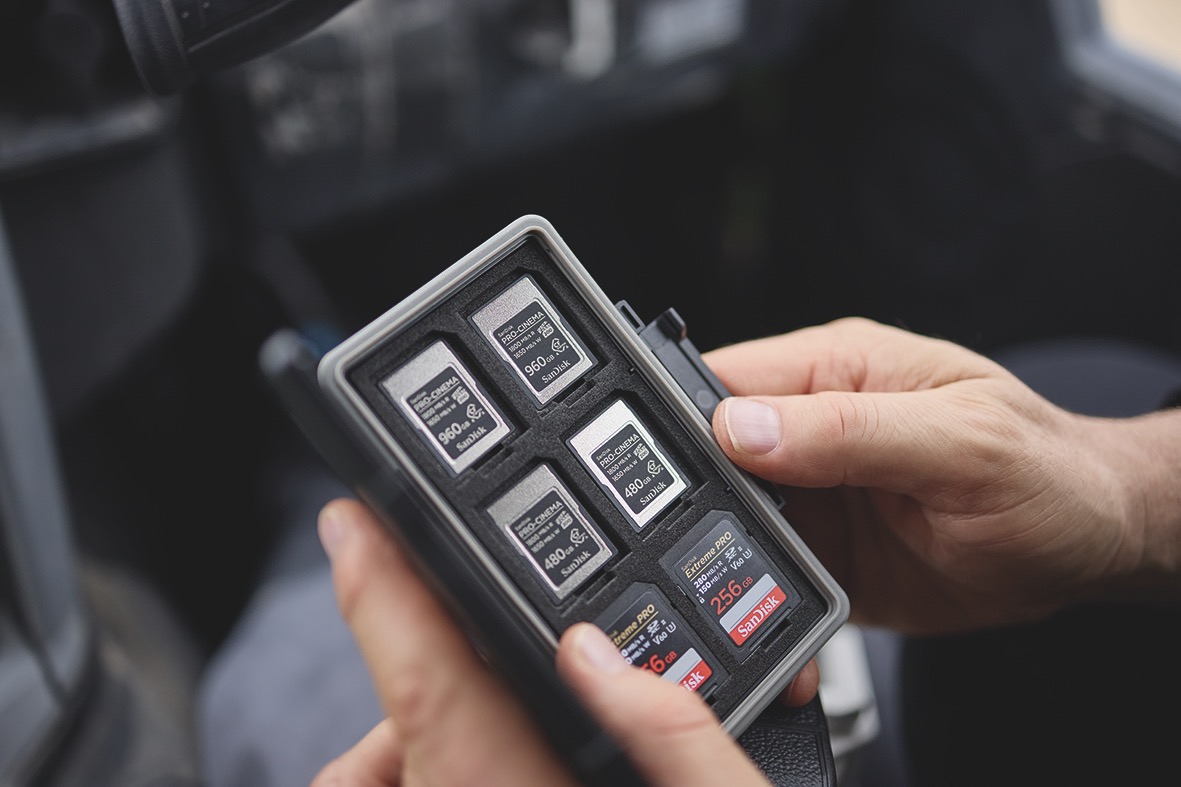 A pair of hands holding a case of six memory cards from Sandisk
