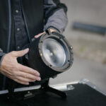 A pair of hands adjusting a round light on a box