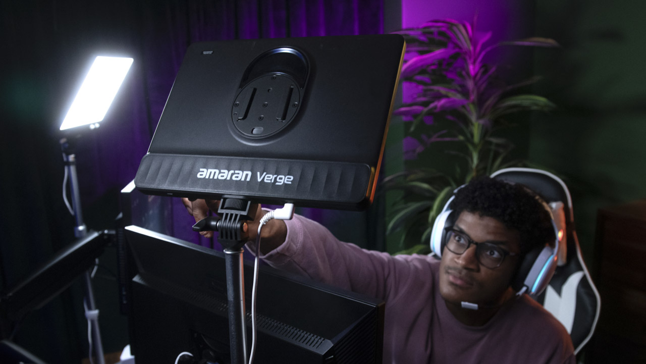 A man sitting on a gaming chair, adjusting two square lights