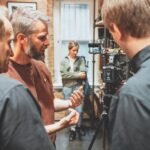 A group of man standing around a professional camera and discussing