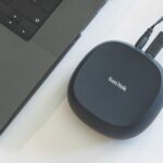 A small rounded square from SanDisk connected to a laptop by two wires