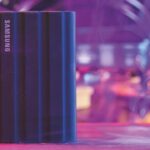 A portable SSD sitting vertically on a table in a purple hall
