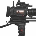 A large professional camera on a tripod with a screen on the side