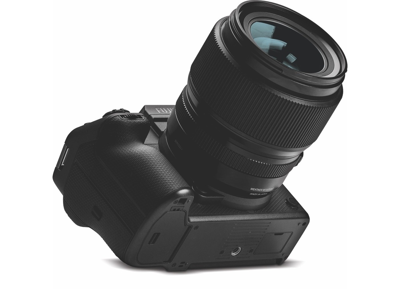 A black camera with a large lens tilted back and facing the upwards diagonal