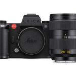 A black camera from Leica with a red logo on the left side. A tall lens sits vertically in front of the camera