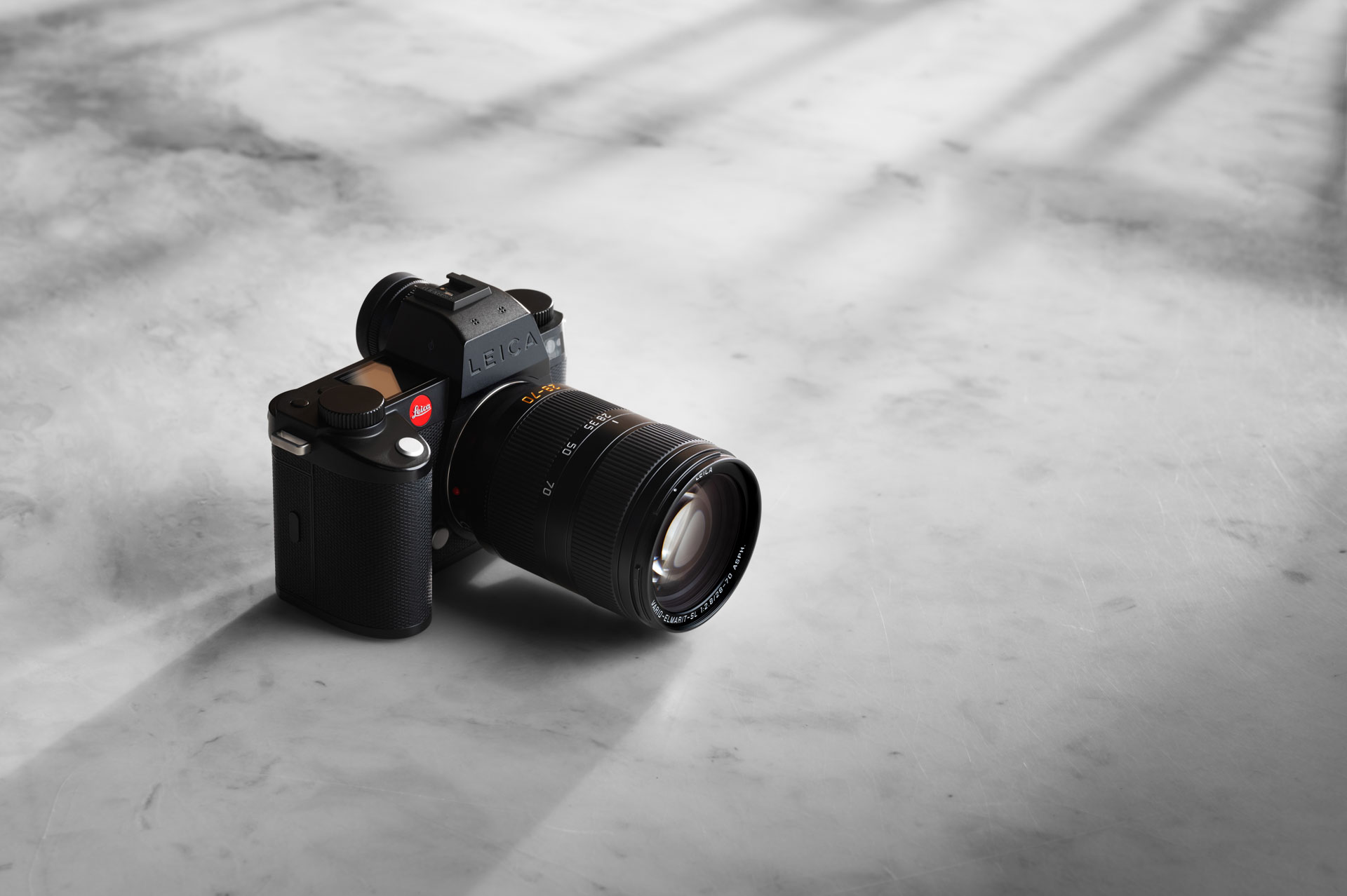 A black camera with a large lens sitting on a stone floor as shadows are cast across the room