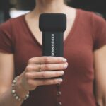 A woman in a red t-shirt holding a rectangular Sennheiser microphone in her hand
