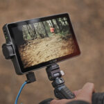 A tablet on a mount being held outside. The screen shows a forest environment