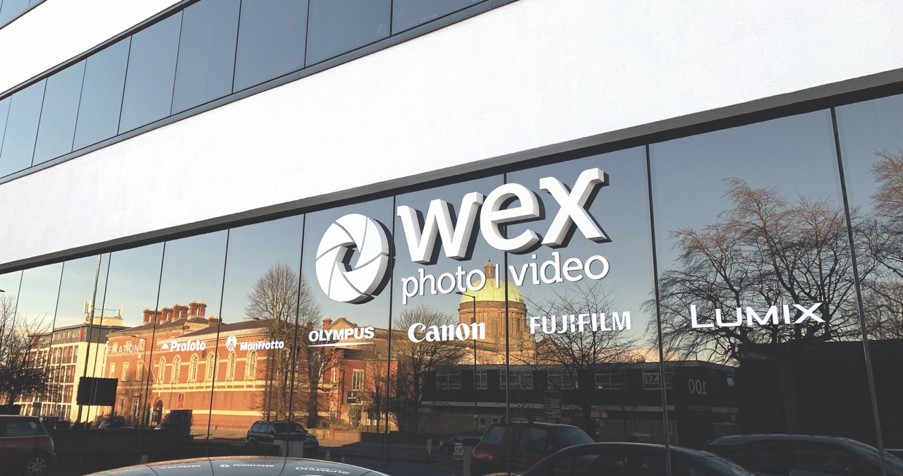 A Wex shop storefront made of glass with white writing on the front