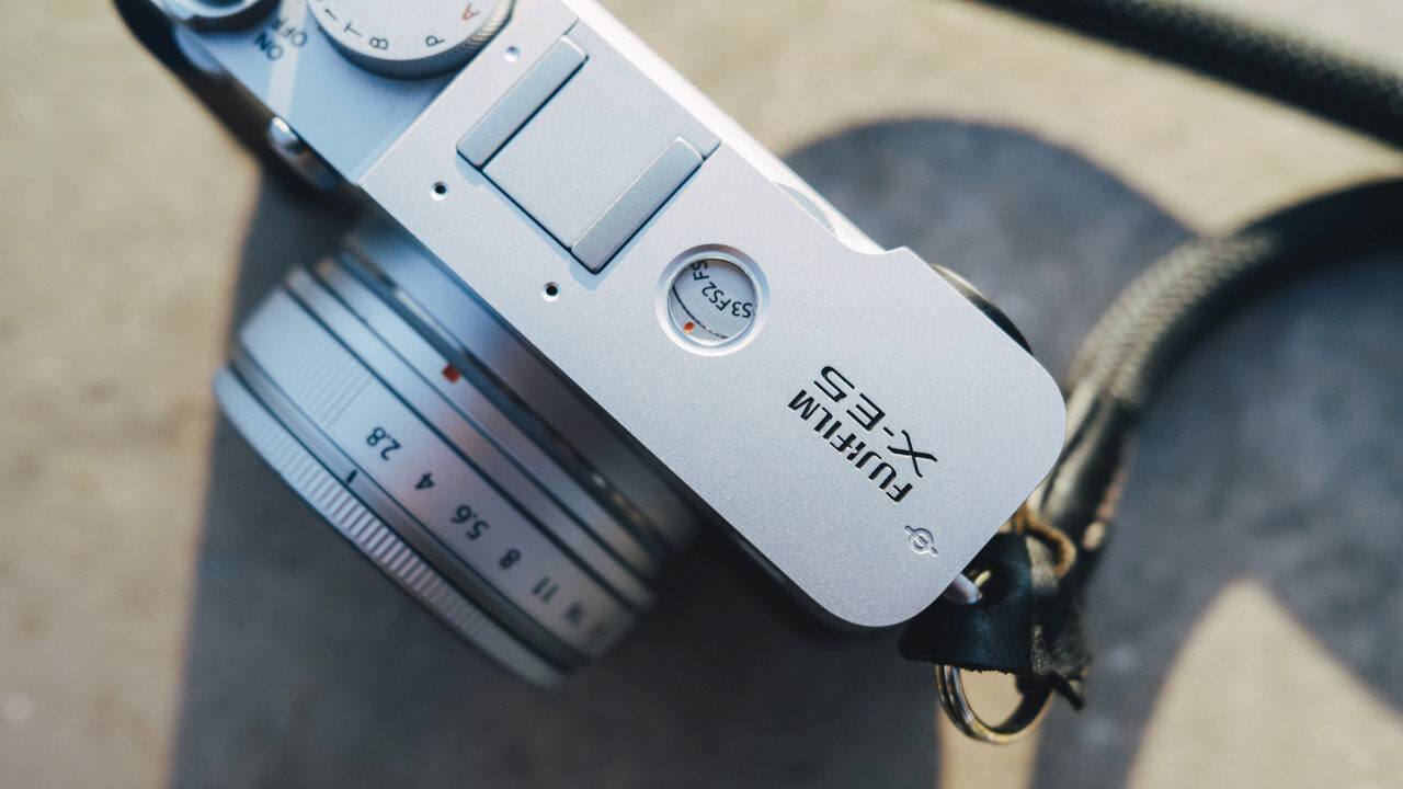 Top-view close-up of a silver camera from Fujifilm sitting on a wall outside