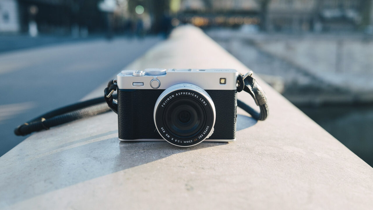 A black and silver camera with a long strap balanced on a slightly curved wall outside