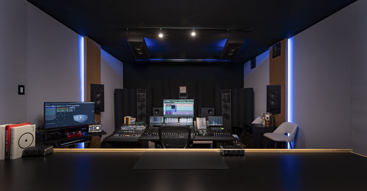 A long, dark recording studio with computers and mixing desks