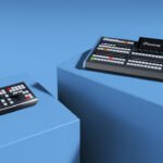 Two panels with multiple buttons and dials sit on blue stands in a blue room