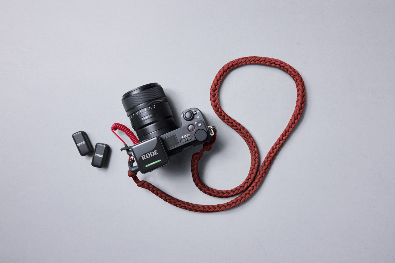 A top-view of a camera with a red cord attached and two small squares next to it