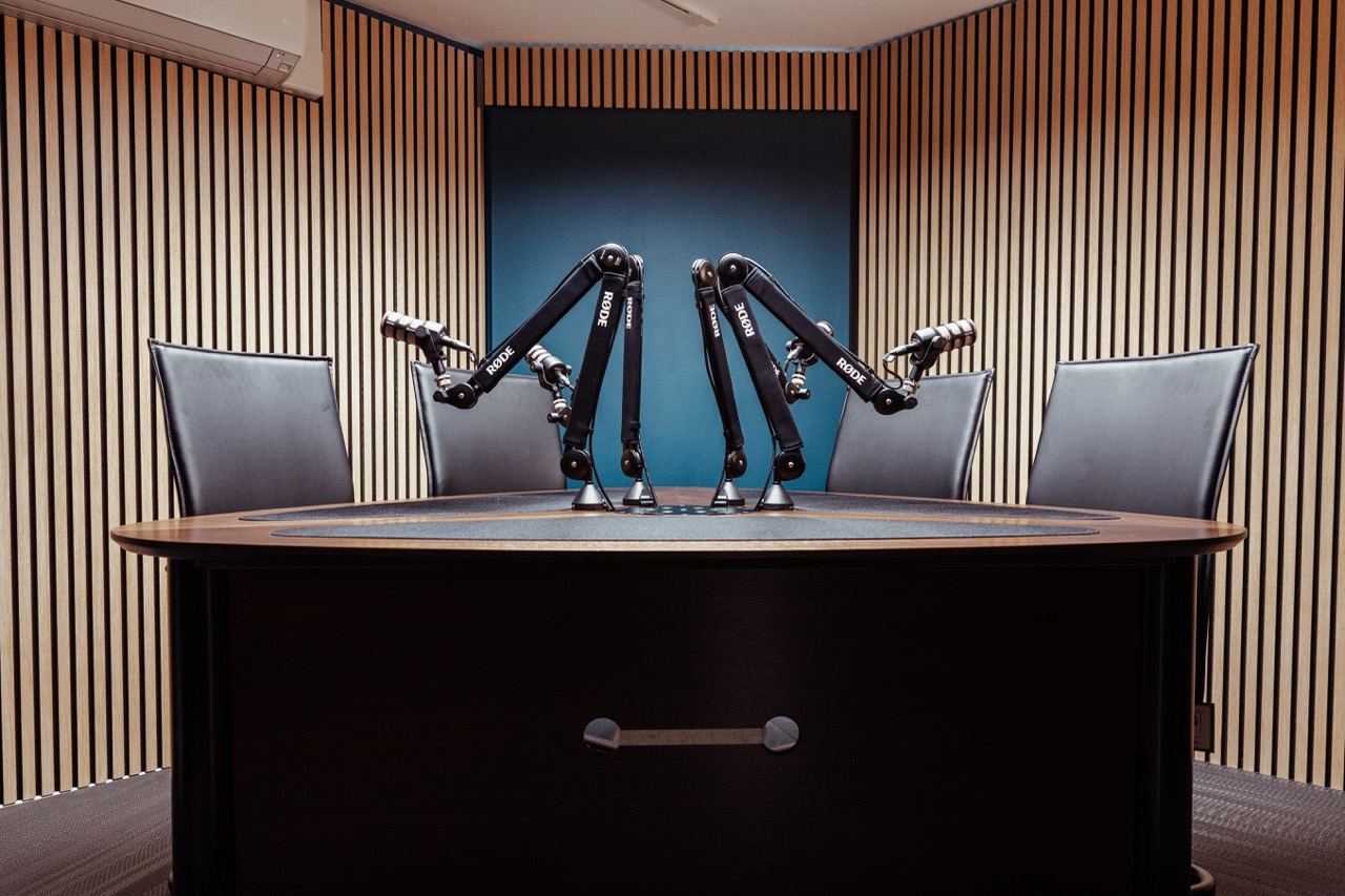 A round desk with cameras on tripods recording and microphones set up on the surface