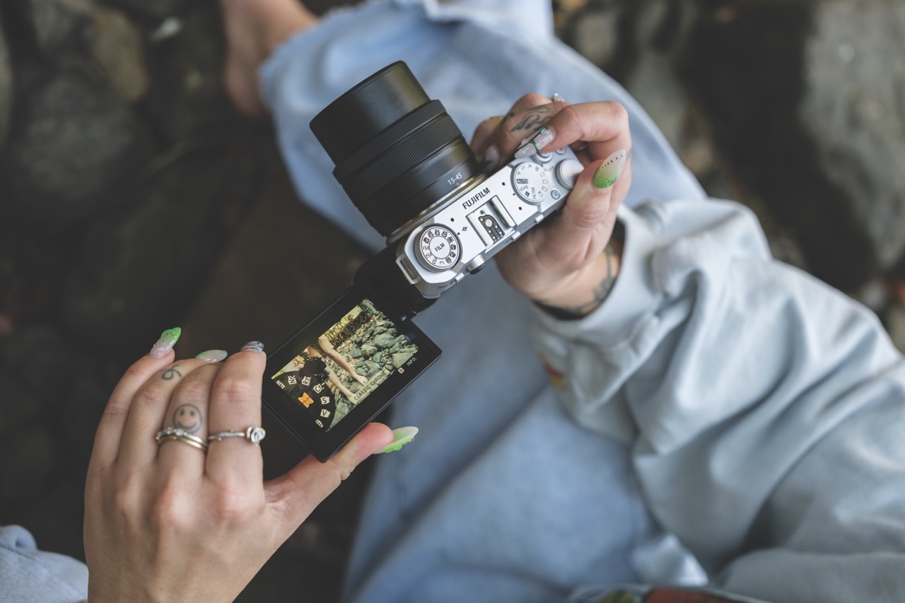 A top view of a camera with a rotating screen. A person with manicured nails adjusts it