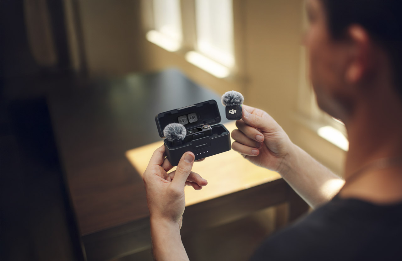 Over the shoulder photo of a man taking two DJI microphones out of a case