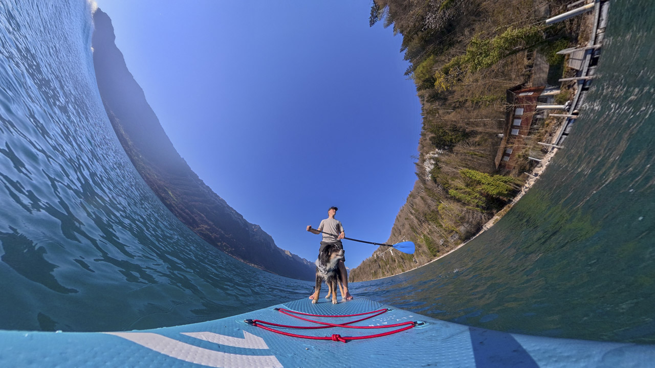 A fish eye lens showings a person on a stand-up paddle board in the sea