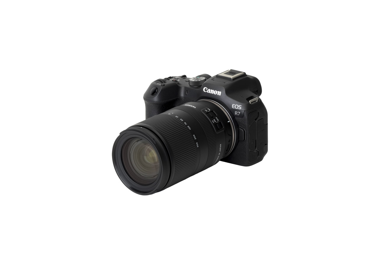 A black camera with a long lens from Tamron, against a white background