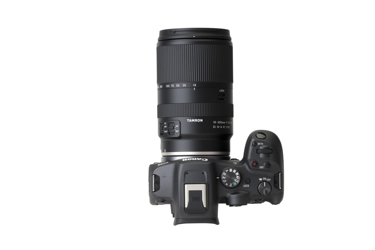Top view of a camera with a large lens from Tamron attached, against a white background