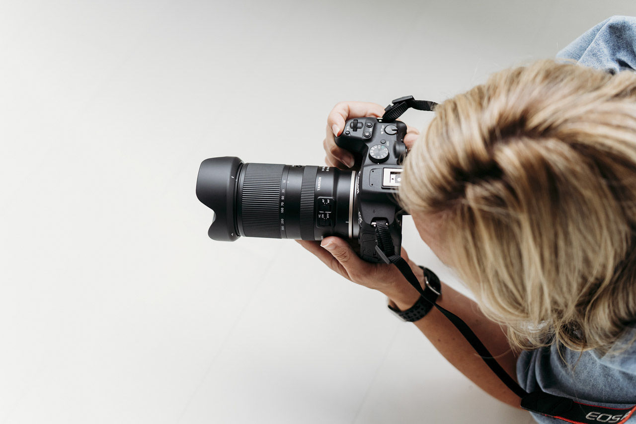 Top view of a person holding a camera with a large lens from Tamron attached