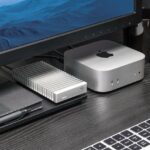 An SSD from OWC next to a rectangular device from Apple, under a computer
