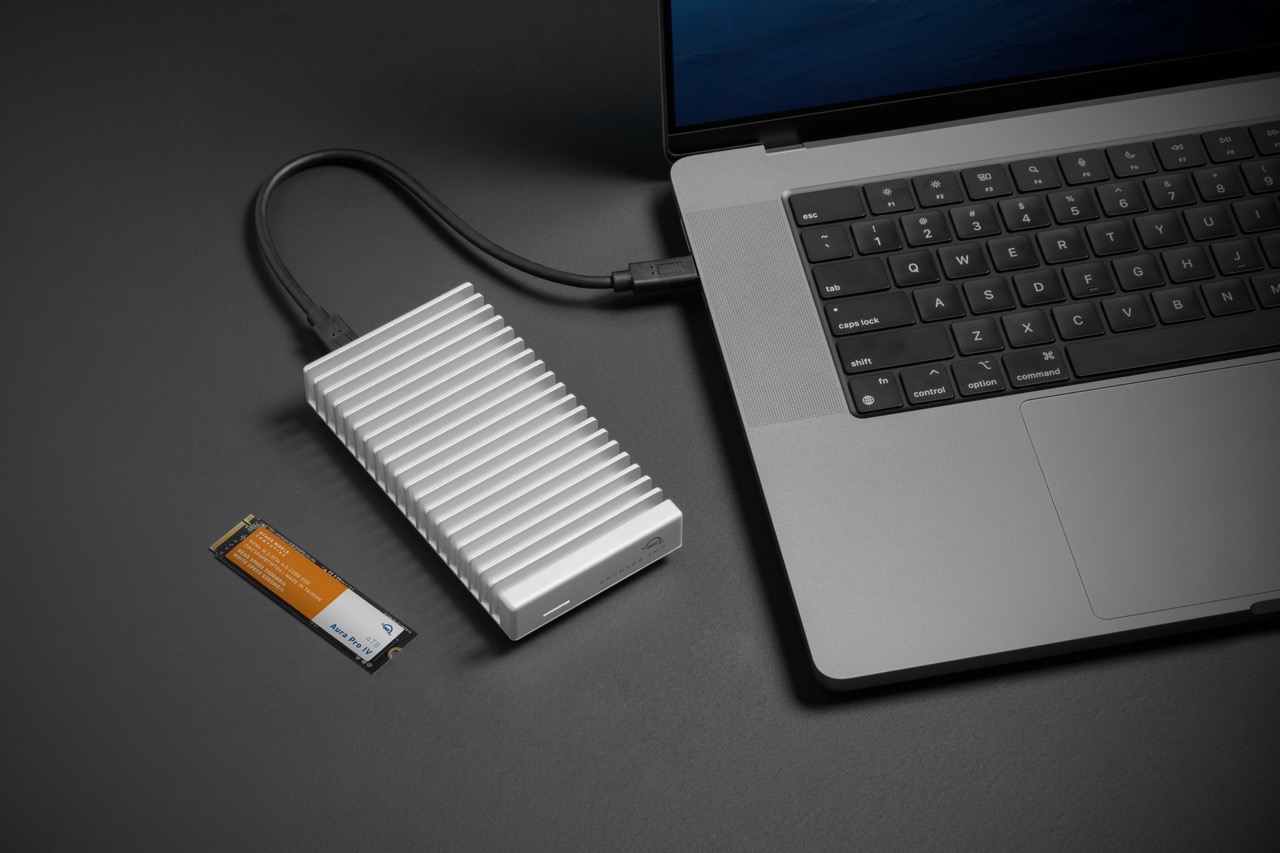 A white SSD from OWC attached to a laptop next to a orange and white rectangle