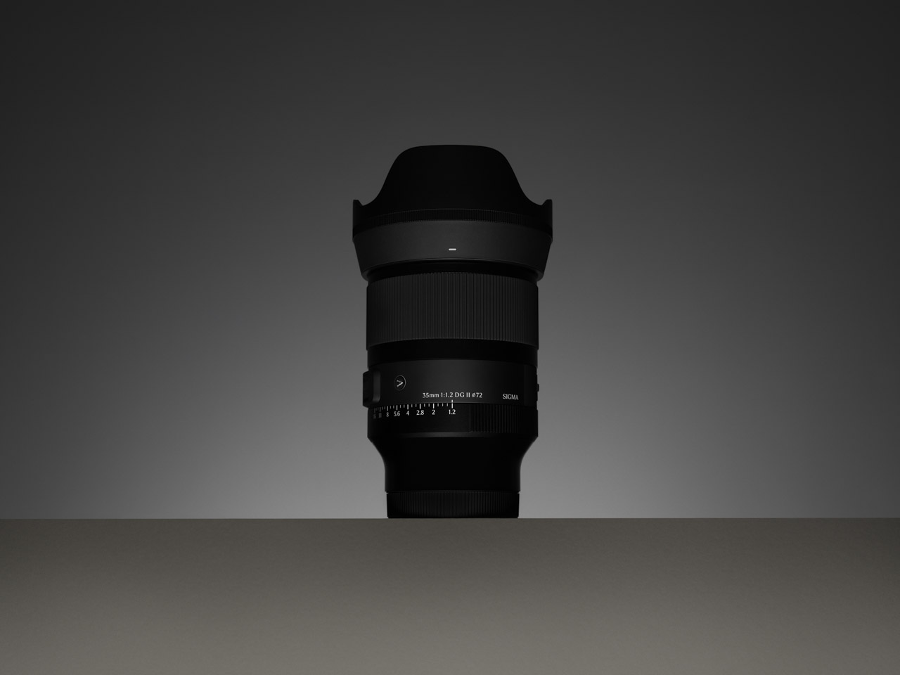 A black lens from Sigma, sitting on a dark surface with dark lighting behind