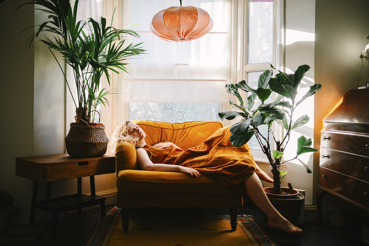 A dimly-lit living room with large plants and orange decor