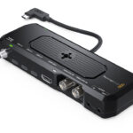 A black device with multiple ports and a wire at the back, against a white background