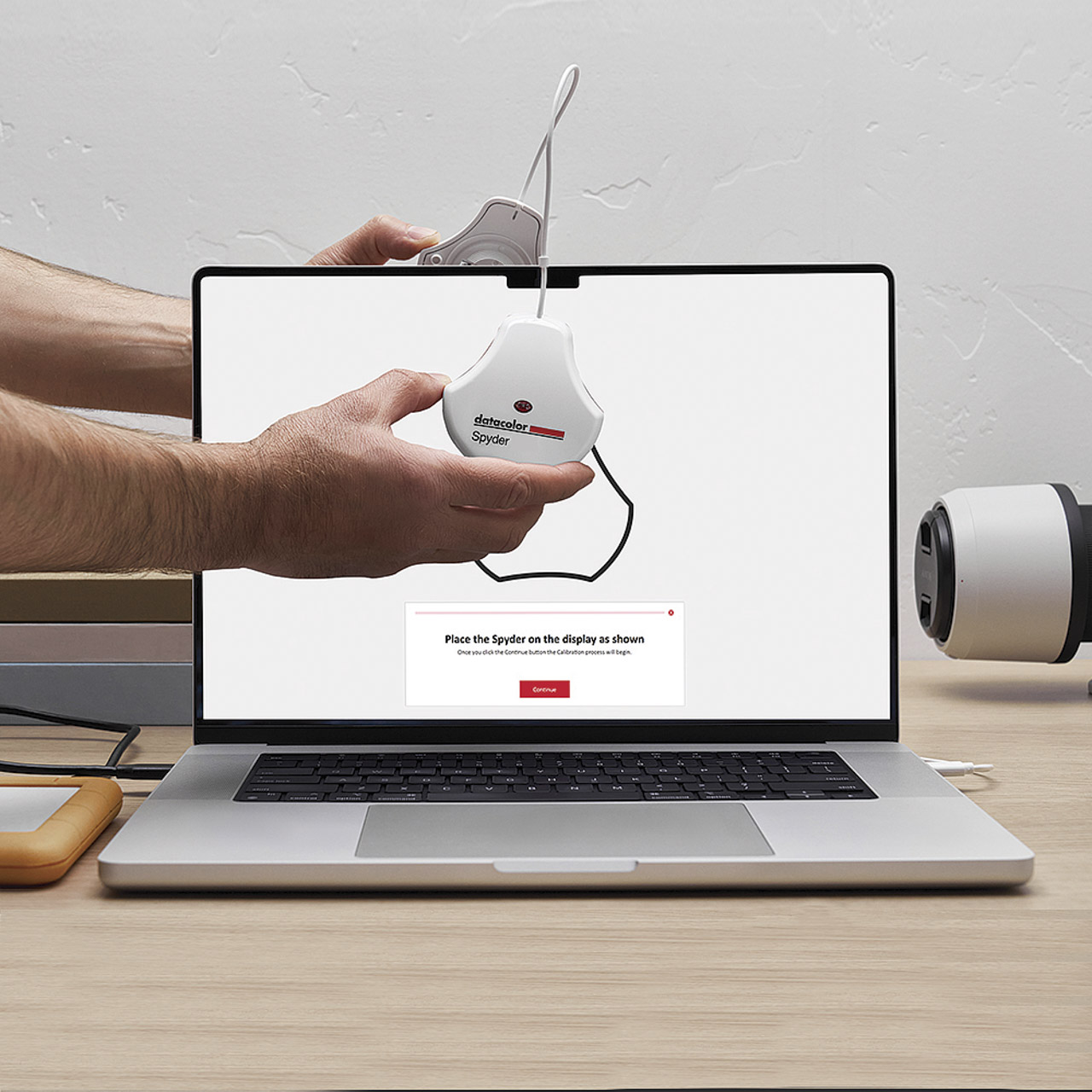 An arm holder a SpyderExpress device in front of an open laptop on a table