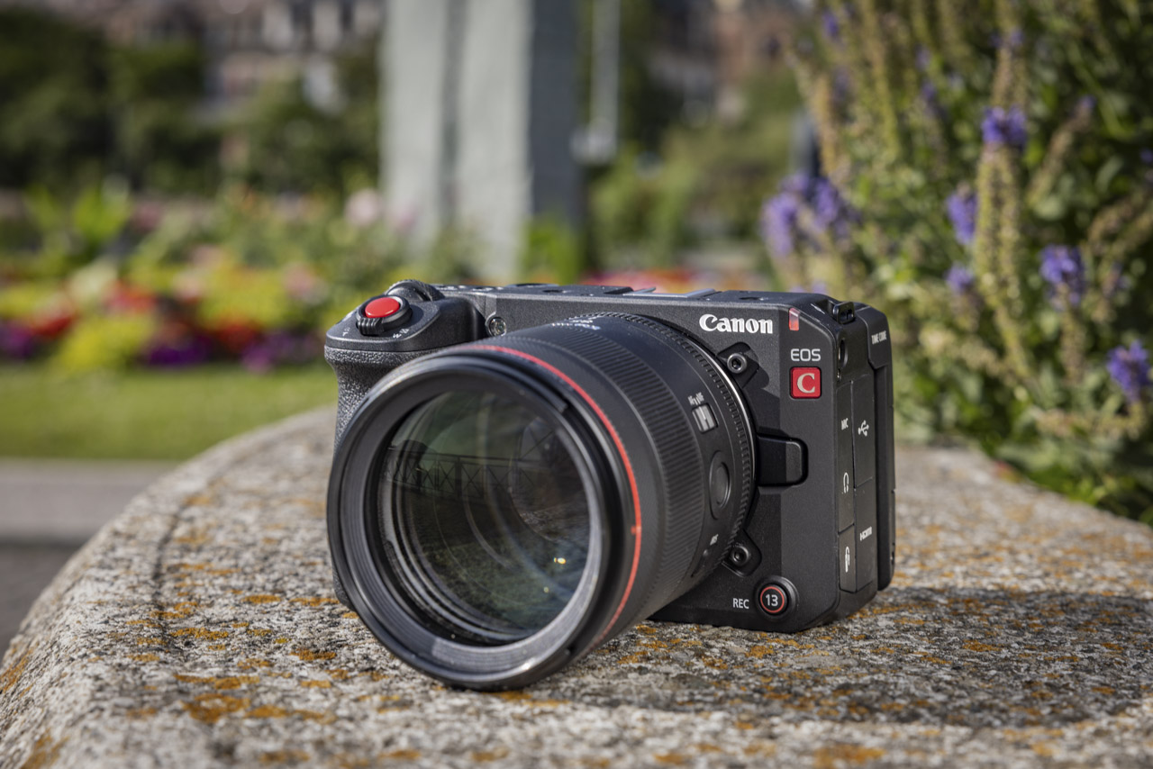 A Canon camera sitting on a stone platform in a flowery garden