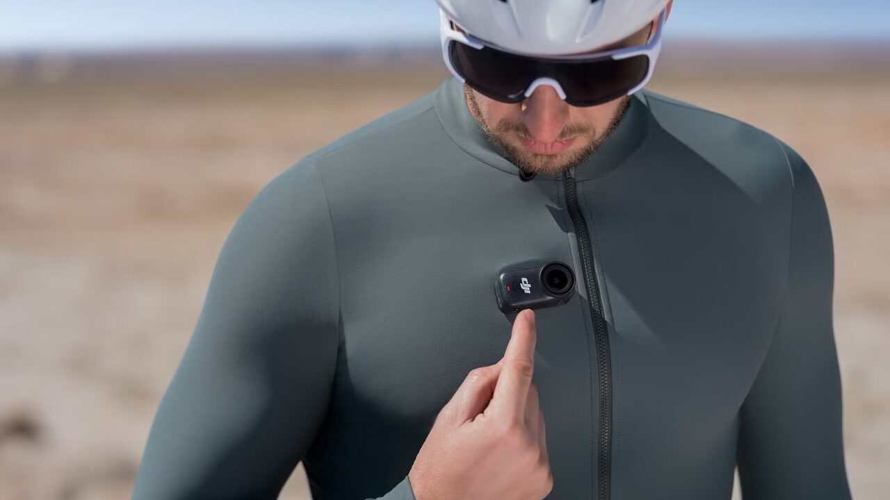 A cyclist pressing a button on a camera by DJI attached to their lycra vest