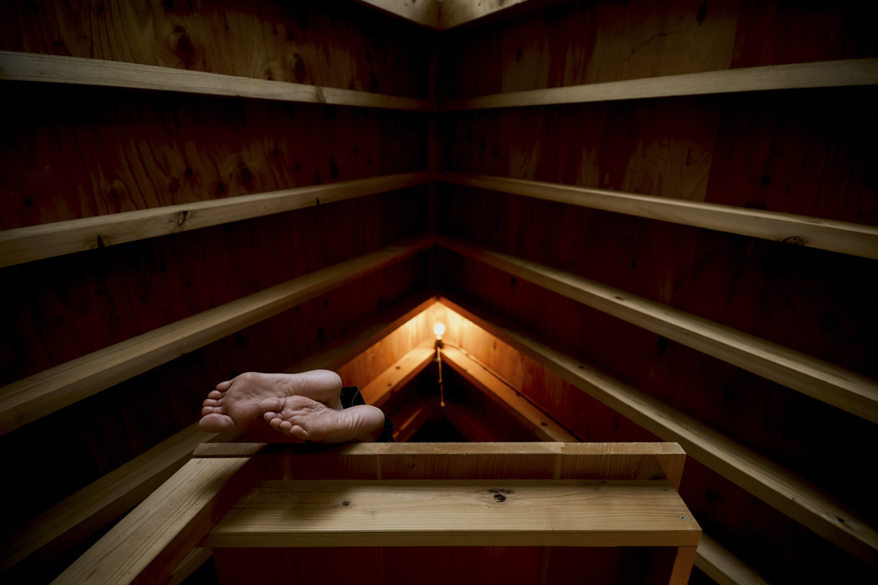 Low view of the wooden roof of a building. A person lies on a table with their feet hanging over