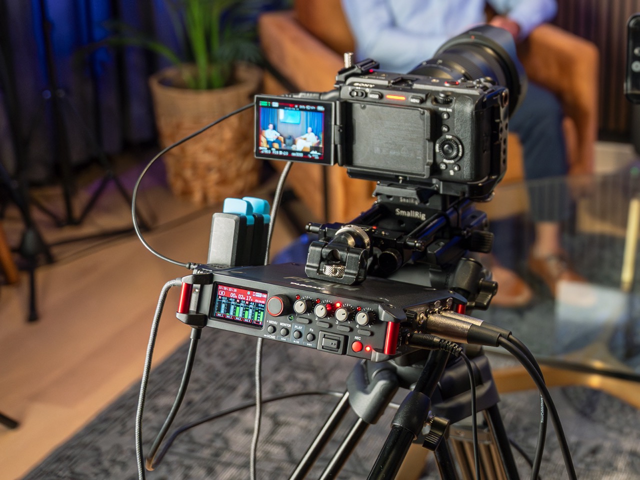 A camera on a mount with a recording device from Tascam attached. It is recording in a living room