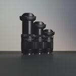 A line of three long lenses from Sigma on a black surface