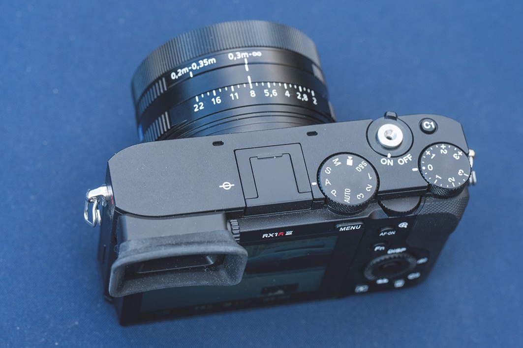The button layout and menus will be familiar to Sony Alpha owners Top-view of a Sony camera with multiple buttons on top, against a blue background